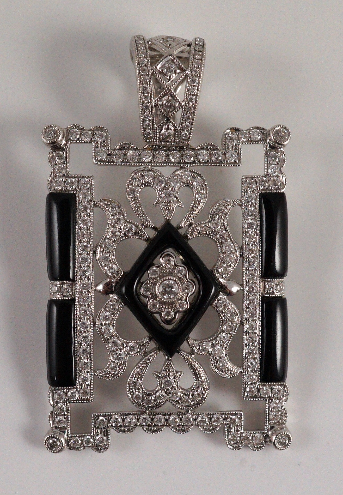 A modern 1920's style pierced 18k white gold, diamond and black onyx set rectangular pendant